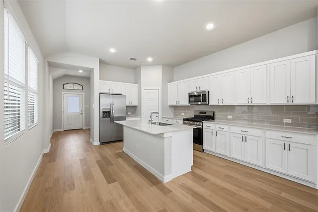 a kitchen with white cabinets and stainless steel appliances