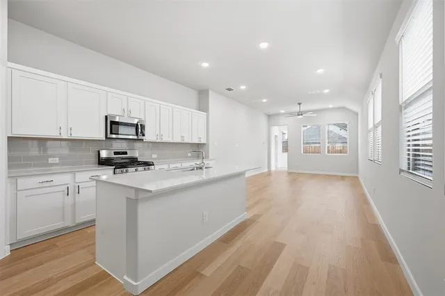 a kitchen with stainless steel appliances granite countertop a stove top oven a sink dishwasher and a refrigerator with wooden floor