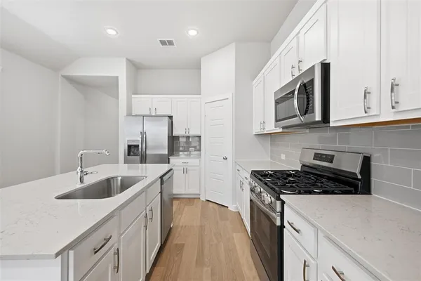 a kitchen with stainless steel appliances granite countertop a sink stove and cabinets