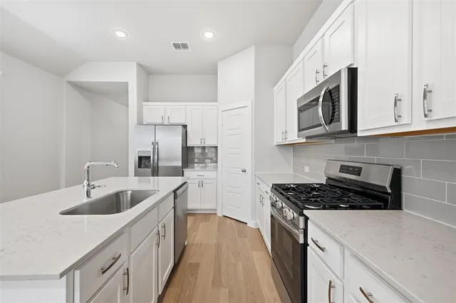 a kitchen with stainless steel appliances granite countertop a sink stove and cabinets