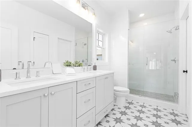 a bathroom with a double vanity sink toilet and shower