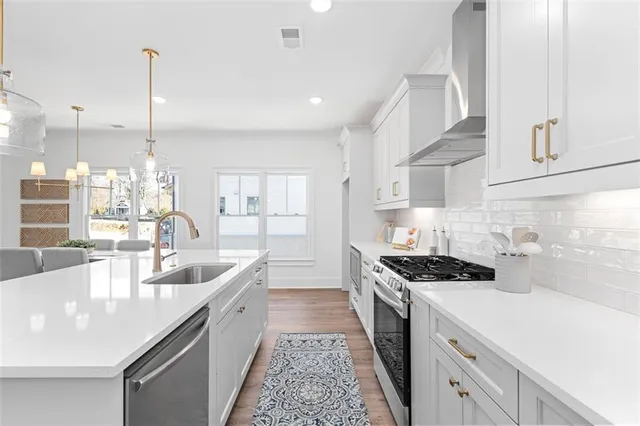 a kitchen with stainless steel appliances granite countertop a sink a stove and a wooden floors