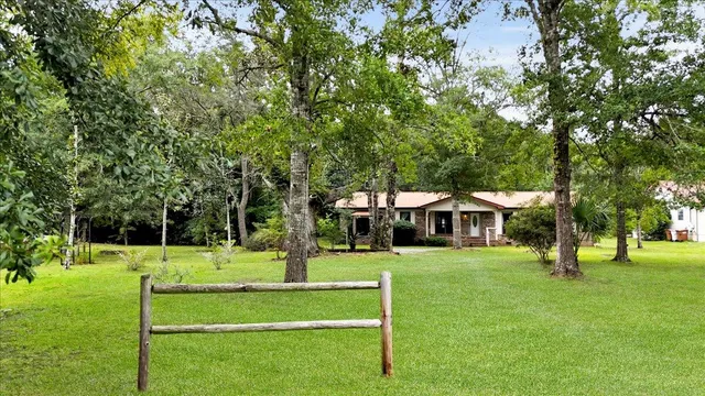 a view of a white house with a big yard and large trees