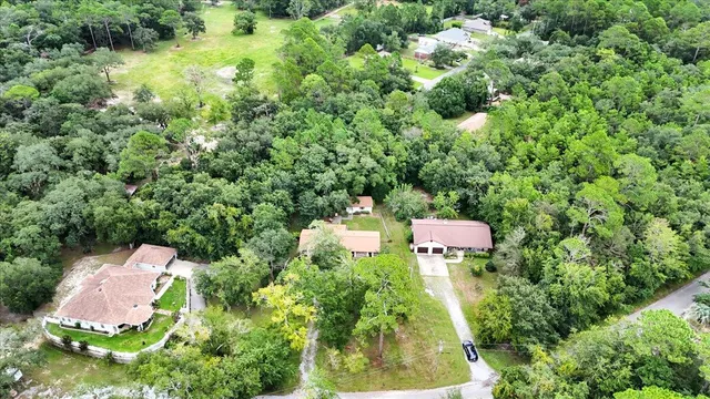 an aerial view of residential house with outdoor space and trees all around