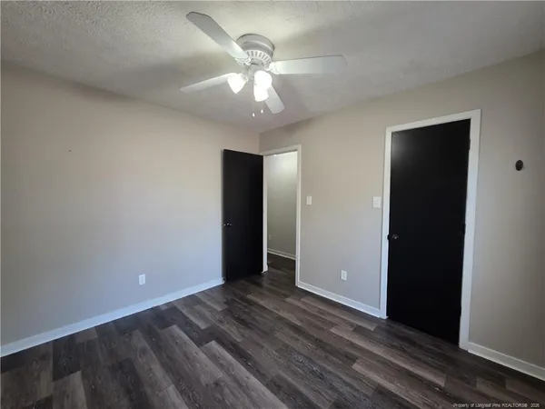 an empty room with closet and a ceiling fan