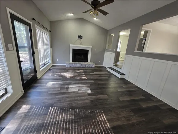 a view of an empty room with wooden floor and a fireplace