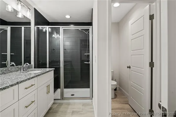 a bathroom with a granite countertop sink two mirror and shower