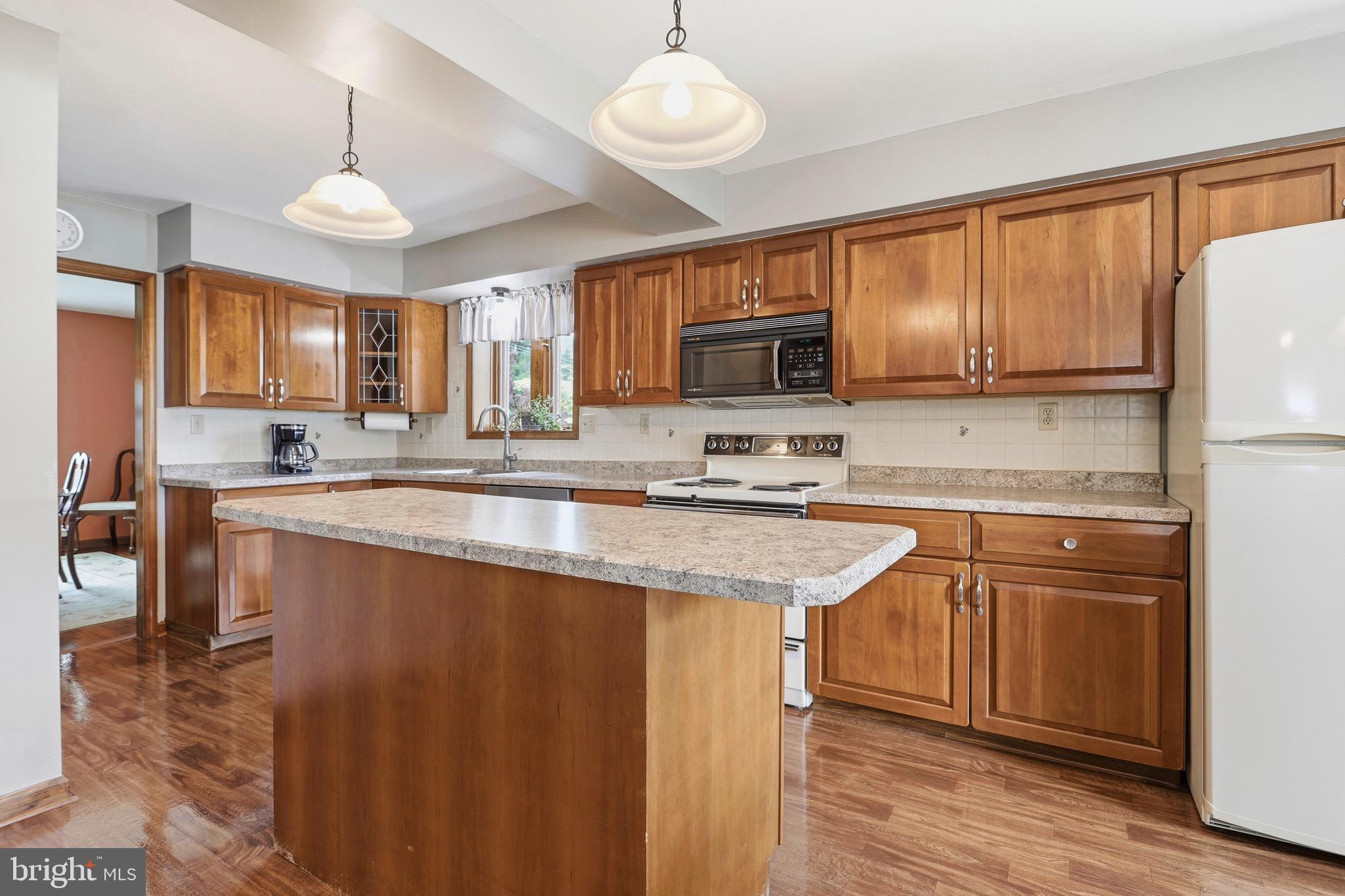 527 Saxer Avenue Springfield, PA 19064 - Photo 11 of 33 a kitchen with stainless steel appliances granite countertop a stove a sink dishwasher and a refrigerator with wooden floor