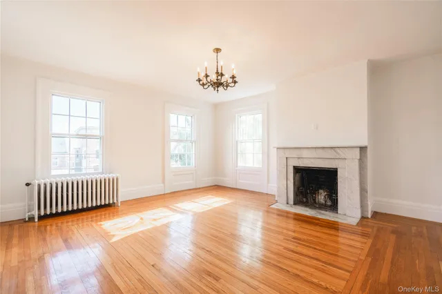 an empty room with wooden floor fireplace and windows