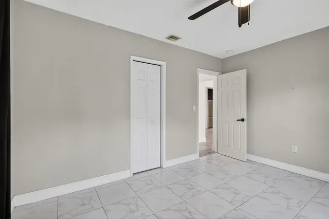 an empty room with windows and fan