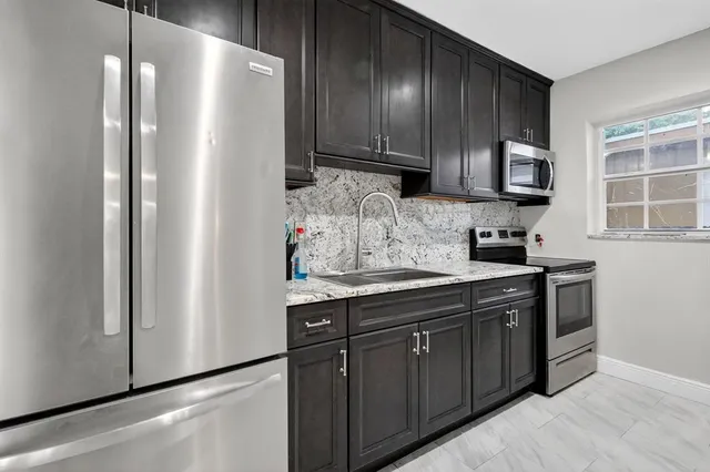 a kitchen with stainless steel appliances granite countertop a refrigerator a sink and cabinets