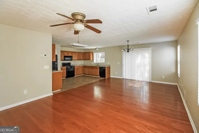 a view of empty room with wooden floor and window