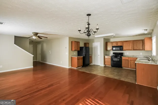 a view of a kitchen with stainless steel appliances granite countertop a refrigerator and a stove top oven