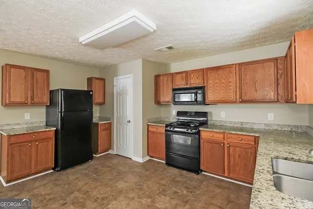 a kitchen with stainless steel appliances granite countertop a refrigerator stove top oven a sink and dishwasher
