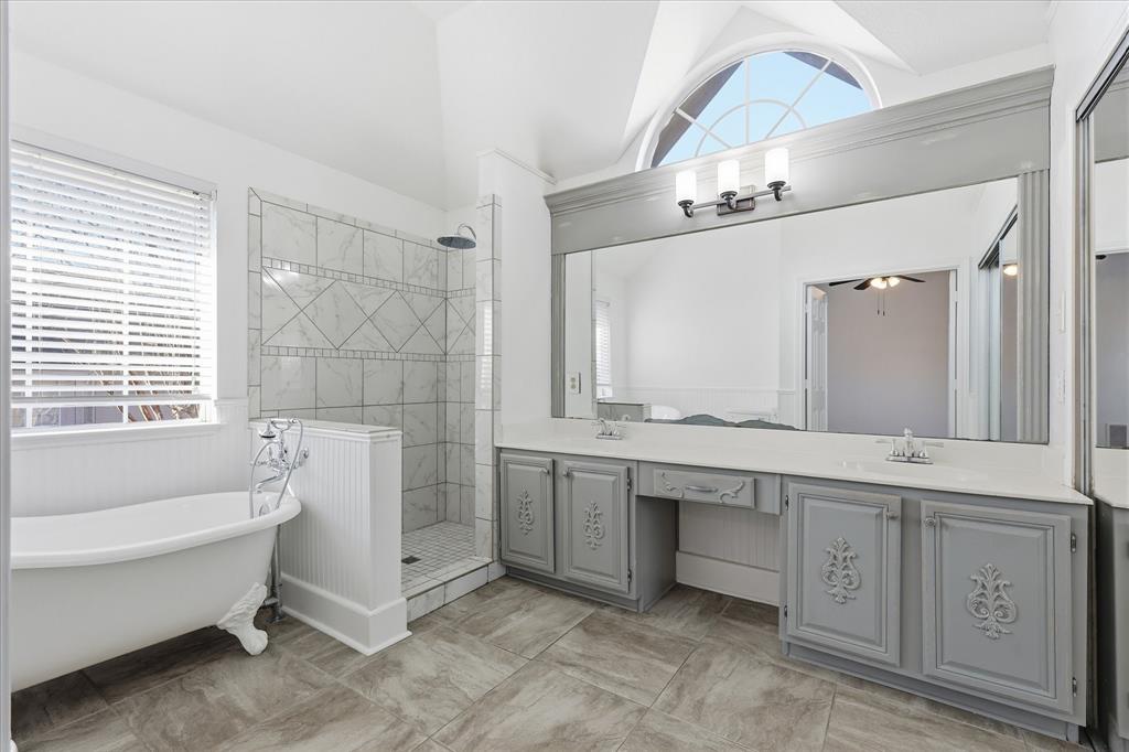5023 Falcon Hollow Road McKinney, TX 75072 - Photo 17 of 25 Bathroom with double vanity, walk in shower, a freestanding bath, vaulted ceiling, and a ceiling fan
