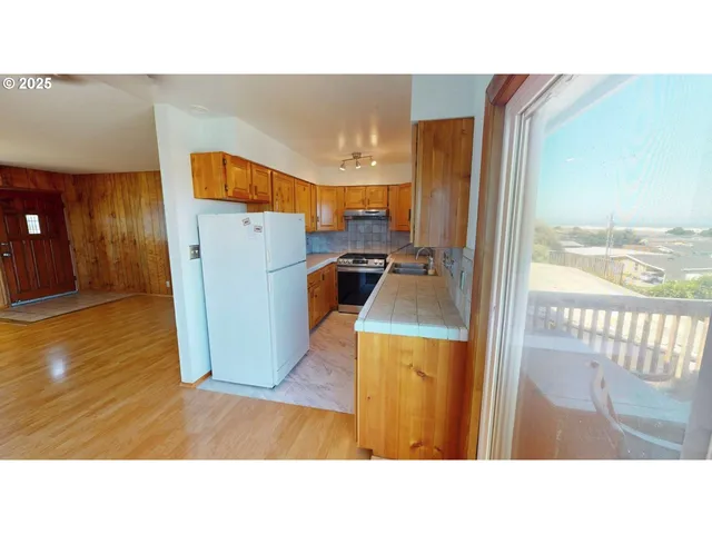 a kitchen with a refrigerator and wooden floor