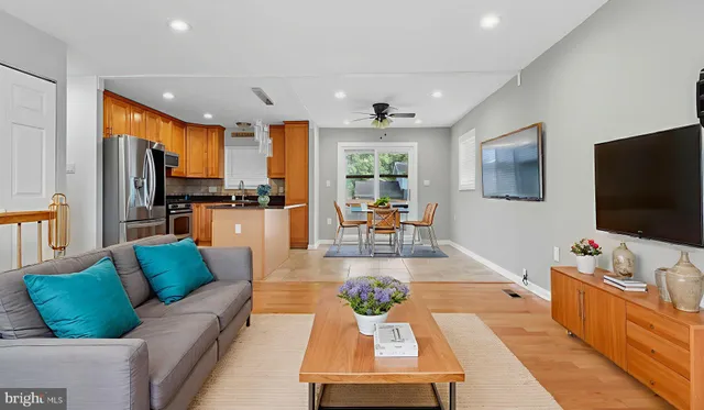 a kitchen with stainless steel appliances kitchen island granite countertop a dining table chairs sink and cabinets