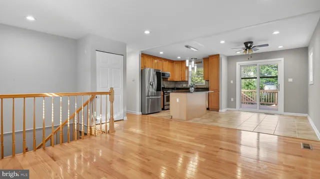 a kitchen with stainless steel appliances granite countertop a refrigerator a stove and a sink with wooden floor