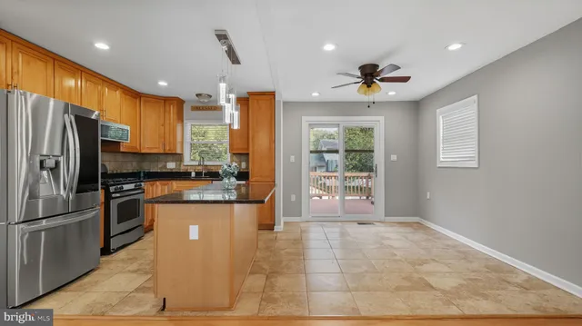 a open kitchen with stainless steel appliances granite countertop a refrigerator a sink dishwasher and a fireplace with wooden floor