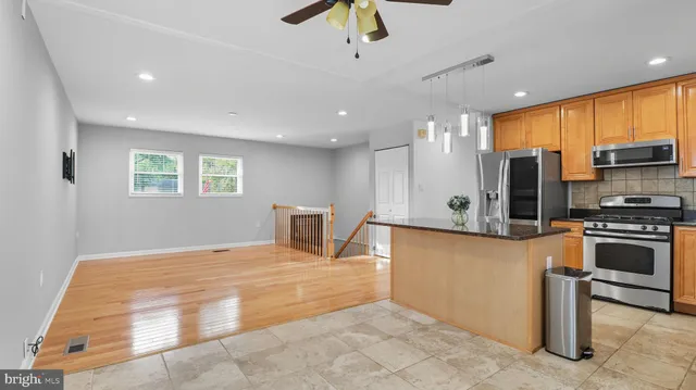 a kitchen with kitchen island a counter top space cabinets and stainless steel appliances