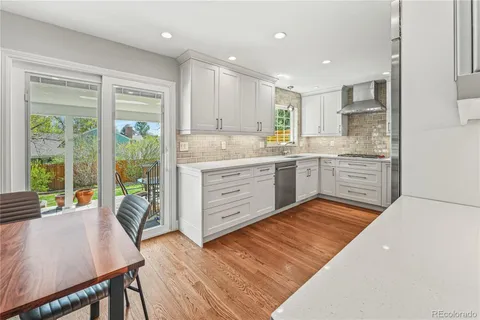 a large kitchen with kitchen island a stove a refrigerator a sink dishwasher with a dining table and chairs with wooden floor