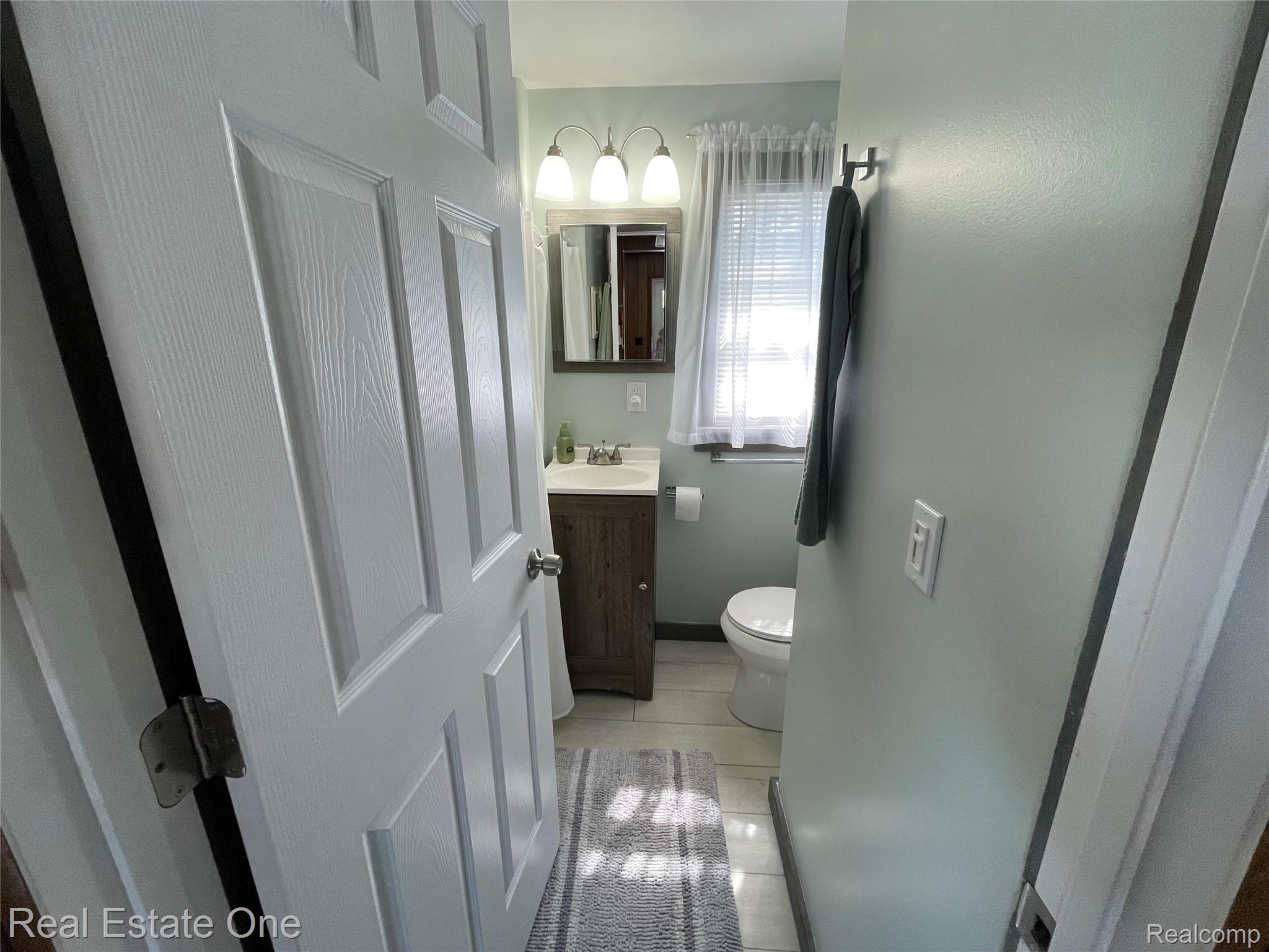 4160 Hawk Road Lincoln, MI 48742 - Photo 35 of 48 Bathroom featuring a wood-finish vanity with a rectangular sink, a wall-mounted mirror, and overhead lighting
