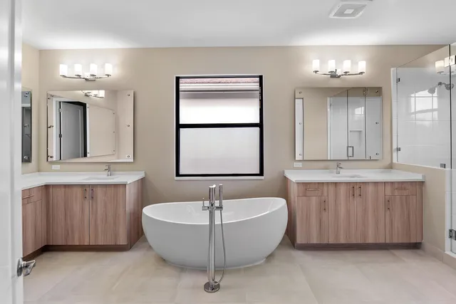 a bathroom with a tub a double vanity sink and a mirror