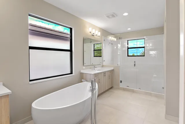 a bathroom with a white tub a sink and mirror