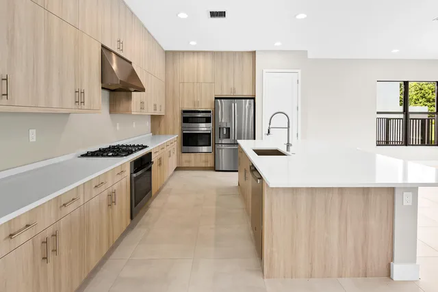 a large kitchen with stainless steel appliances granite countertop a stove a sink and a refrigerator