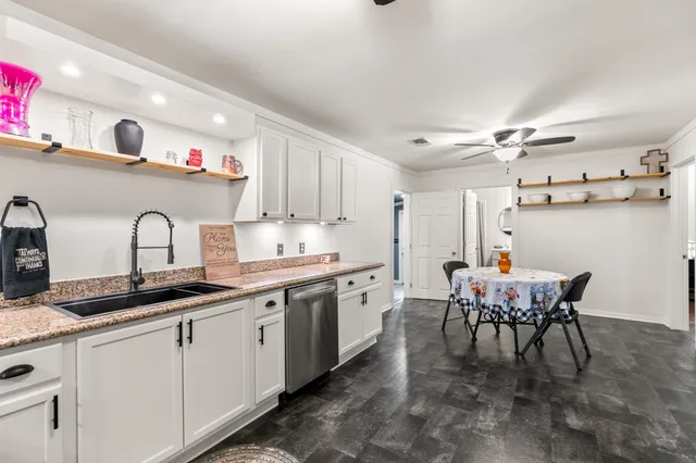 a kitchen with stainless steel appliances granite countertop a stove top oven a refrigerator a dining table and chairs with wooden floor