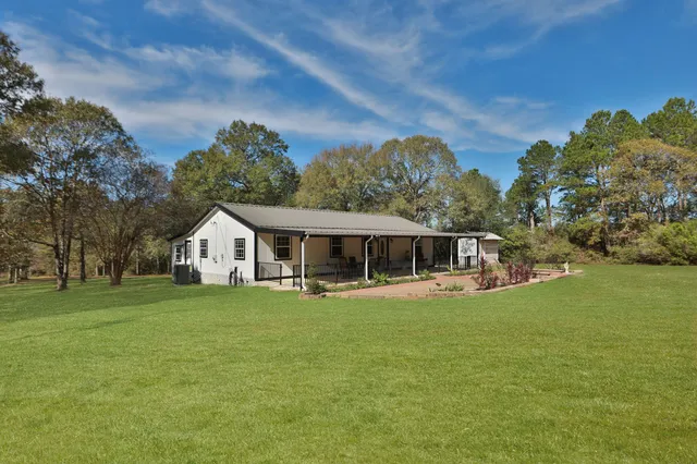a view of a house with a big yard and large trees