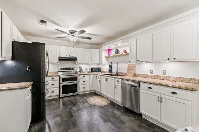 a kitchen with granite countertop a sink stainless steel appliances and cabinets