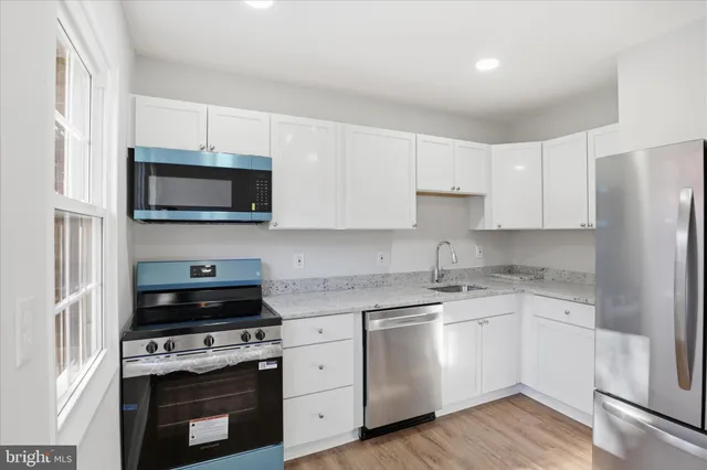 a kitchen with cabinets stainless steel appliances a sink and wooden floor