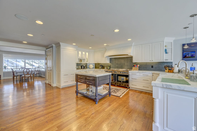 9699 Bypass Road, Unit 5 Alta, UT 84092 - Photo 24 of 54 Gourmet kitchen featuring white cabinetry, light wood-finish flooring, a central island with a stone countertop, a large range with a custom hood, and a dining area with expansive windows