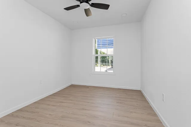 an empty room with a window and a fan
