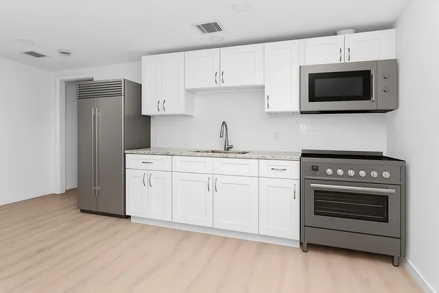 a kitchen with white cabinets stainless steel appliances and sink