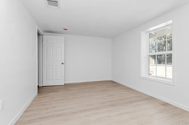 an empty room with wooden floor and windows