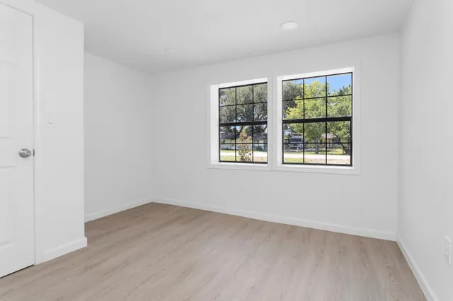 an empty room with wooden floor and windows