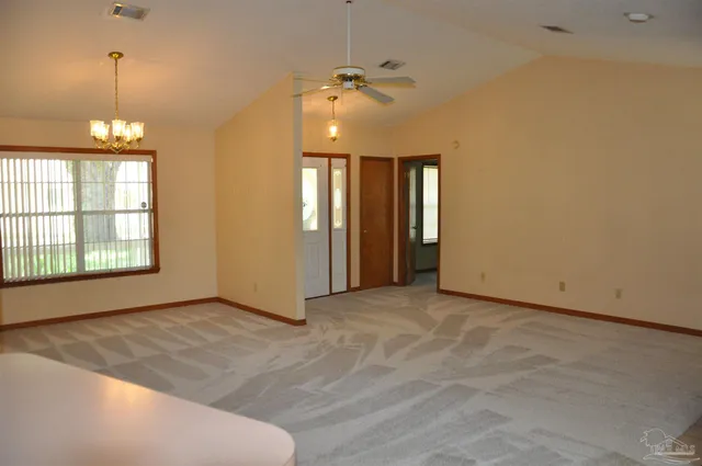 an empty room with windows and chandelier fan