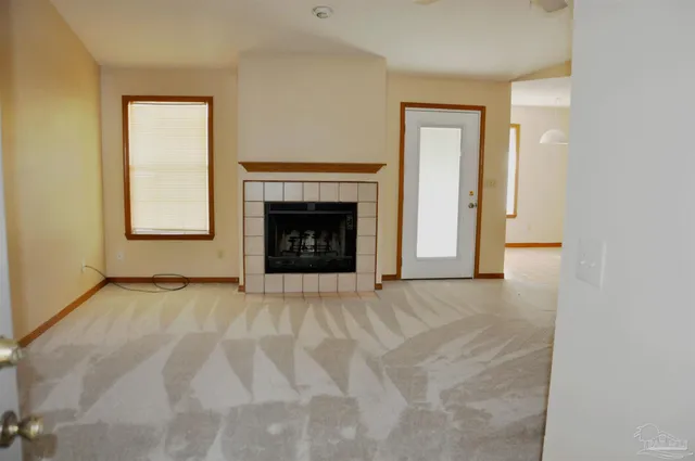 a view of an empty room with a fireplace and a window