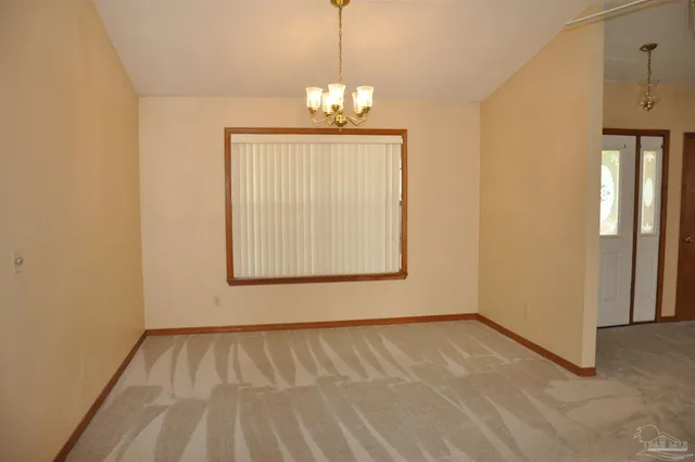 a view of an empty room with window chandelier fan