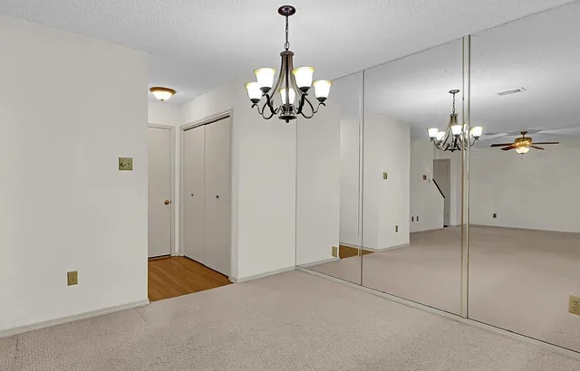 a view of an empty room with chandelier fan