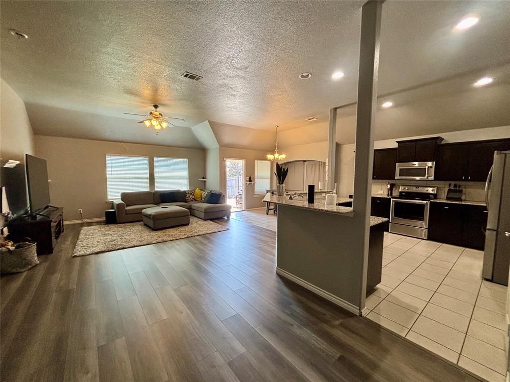 900 Grouse Road Glenn Heights, TX 75154 - Photo 7 of 13 a living room with stainless steel appliances kitchen island granite countertop a refrigerator a sink dishwasher a oven and a dining table with wooden floor