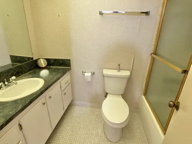 a bathroom with a granite countertop toilet sink and mirror