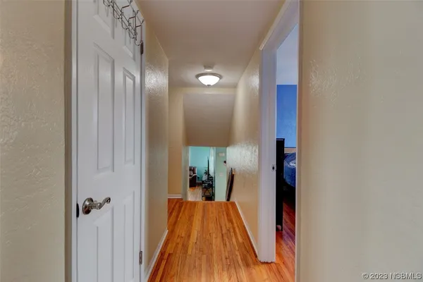a view of a hallway with wooden floor and a bathroom