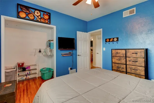 a bedroom with a bed and a flat tv screen on dresser