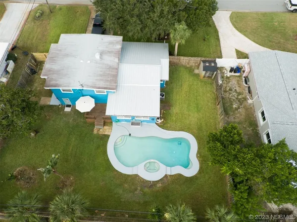 an aerial view of a house with swimming pool and trees
