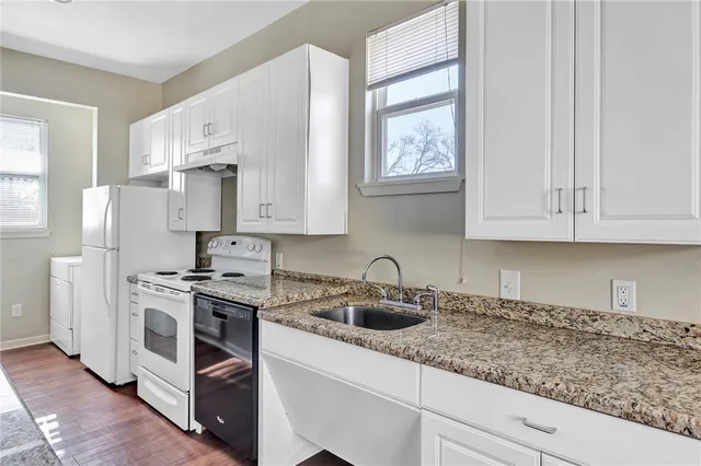 a kitchen with stainless steel appliances granite countertop white cabinets a sink a stove a refrigerator and white cabinets