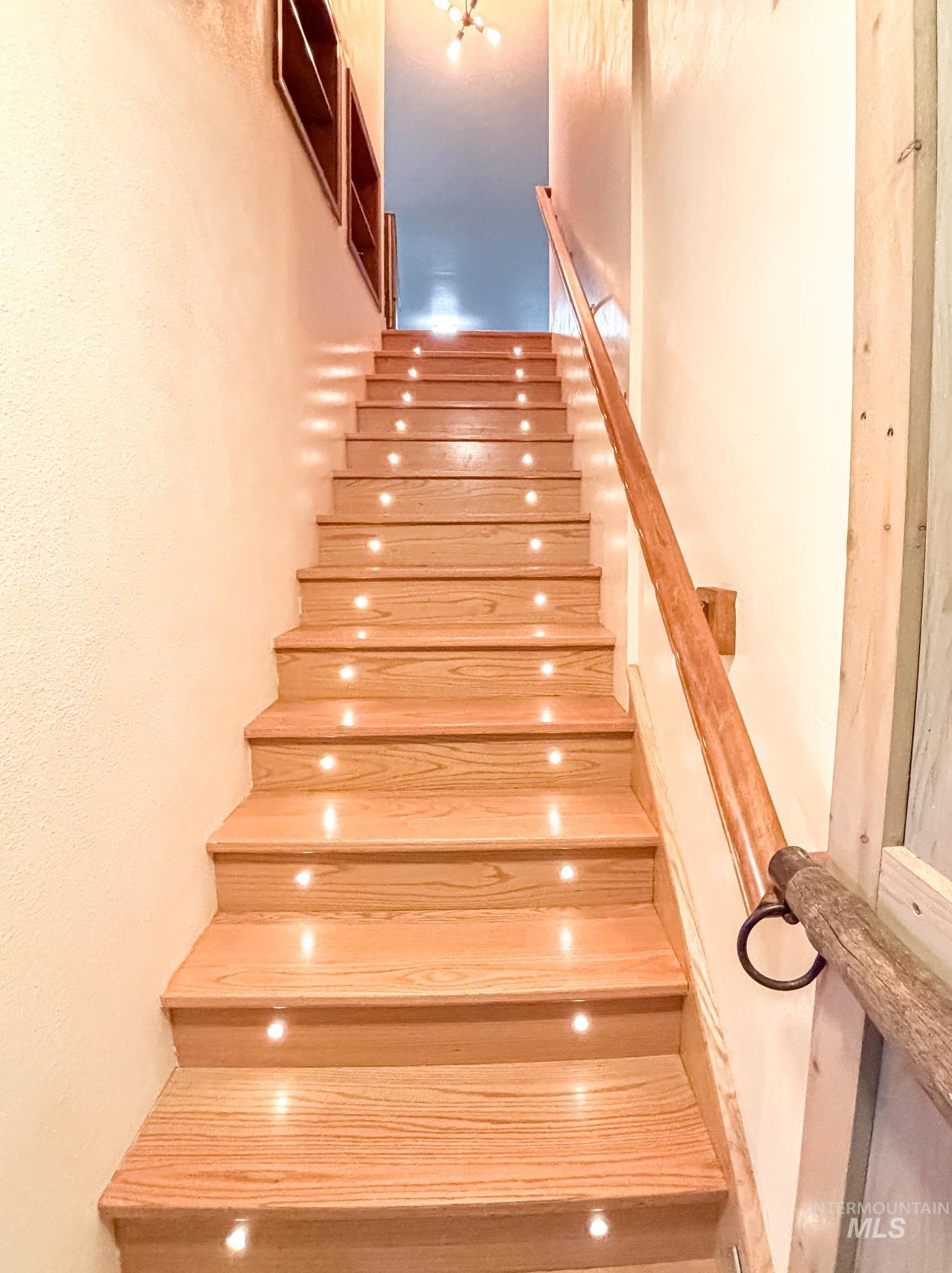1995 Glenwood Road Kamiah, ID 83536 - Photo 19 of 38 Hardwood staircase with integrated step lighting and a wood handrail