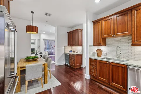 a kitchen with a refrigerator a stove top oven a sink dishwasher and wooden cabinets with wooden floor